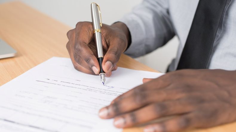 Homem negro assinando um documento Homem negro assinando um documento